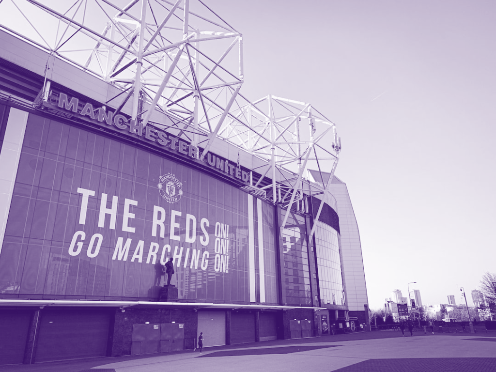 Old Trafford football ground with "Reds go marching on" slogan.